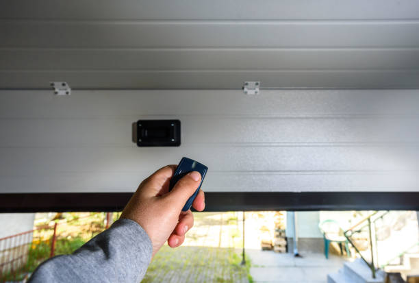 A person uses a remote to open a garage door, illustrating smart garage door openers.